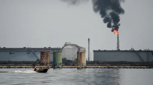 صورة تظهر منصة نفطية في فنزويلا مع دخان أسود يتصاعد من شعلة، وقارب صغير يمر بالقرب من المرافق النفطية.