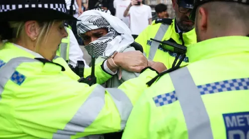 اعتقال ناشط يرتدي غطاء رأس فلسطيني خلال احتجاج على حظر منظمة العمل الفلسطيني، مع وجود ضباط شرطة في الخلفية.