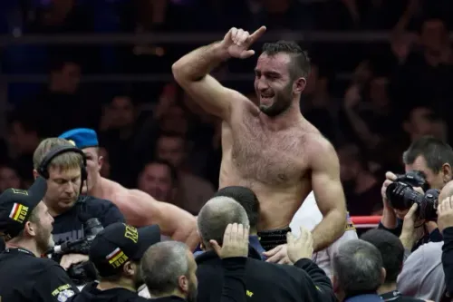 بطل الملاكمة الثقيل Agit Kabayel يحتفل بفوزه بلقب WBC وسط جمهور ومصورين، مع التركيز على انتصاره التاريخي كأول بطل ألماني منذ 1932.