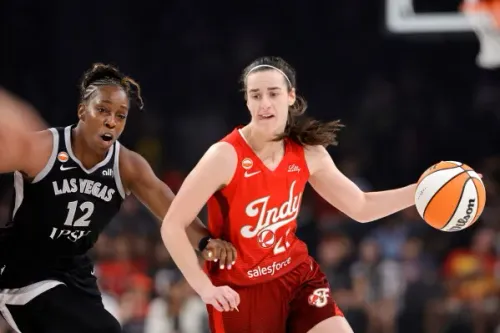 لاعبة كرة سلة من فريق Indiana Fever تحمل الكرة وتتفادى دفاع لاعبة فريق Las Vegas Aces خلال مباراة WNBA.