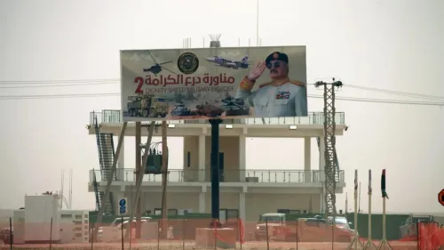 لافتة إعلانية كبيرة تُظهر صورة عسكرية مع نص عربي يشير إلى "درع الكرامة 2"، تعكس الأجواء العسكرية في ليبيا.