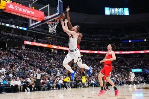 كريستيان براون يسجل نقطة خلال مباراة دنفر ناجتس، مع حارس منافس يحاول التصدي له، في أجواء حماسية بالملعب.