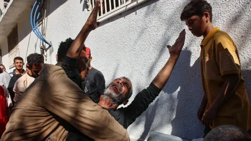 رجل مسن يُعبر عن حزنه وسط مجموعة من الرجال والشبان في غزة، في مشهد يعكس معاناة المدنيين خلال الحرب.