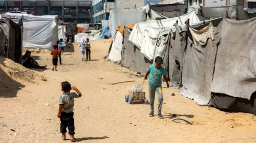 أطفال يلعبون في مخيم للاجئين الفلسطينيين، يظهرون بين الخيام البيضاء والرمادية في بيئة قاحلة، تعكس معاناة اللاجئين.