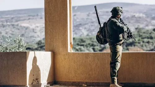 جندي إسرائيلي يقف حارسًا على موقع عند الحدود مع سوريا، ويظهر المنظر الطبيعي للمرتفعات.