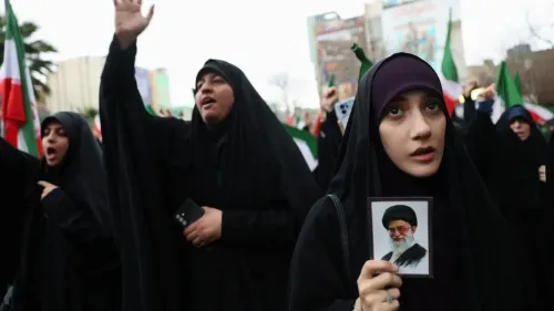 امرأة ترتدي الحجاب تحمل صورة للمرشد الأعلى الإيراني، بينما تشارك في مظاهرة مع حشود ترفع الأعلام الإيرانية.