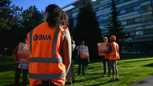 أطباء يرتدون سترات برتقالية تحمل شعار الجمعية الطبية البريطانية (BMA) أثناء احتجاج، مطالبين بتحسين الأجور وظروف العمل.