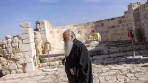 كاهن مسيحي مسن في كنيسة حجرية قديمة في قرية الطيبة بالضفة الغربية، وسط أجواء هدوء تعكس التوترات المستمرة مع المستوطنين.