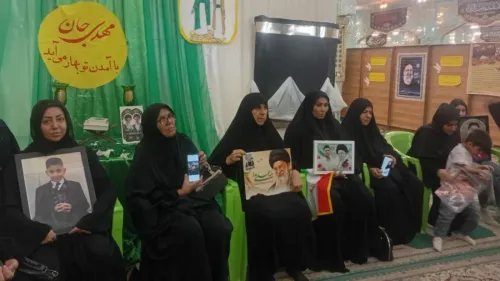 نساء يرتدين الحجاب الأسود يجلسن في قاعة، يحملن صورًا لأحبائهن، مع خلفية مزينة بالأخضر، تعبيرًا عن الحزن بعد الهجوم على لامرد.