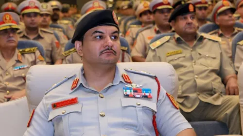 رجل يرتدي زيًا عسكريًا يجلس في مقدمة قاعة مليئة بالضباط، مع التركيز على ملامح وجهه الجادة.