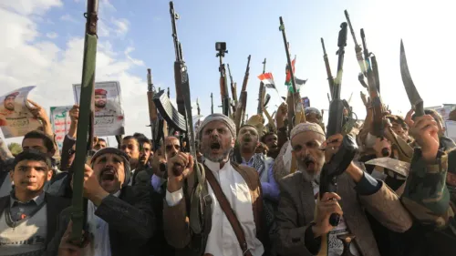 محتجون يمنيون يحملون أسلحة ويرفعون لافتات، معبرين عن ولائهم للحوثيين، وسط أجواء من التوترات السياسية في المنطقة.