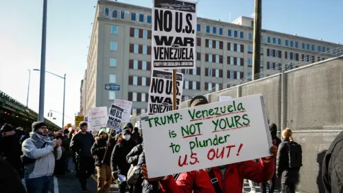 محتجون يحملون لافتات معارضة للتدخل الأمريكي في فنزويلا، بما في ذلك رسالة تدعو ترامب لعدم نهب البلاد.