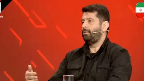 محلل أمني إيراني يتحدث في برنامج تلفزيوني عن استعداد الجيش الإيراني للتحرك ضد الإمارات والبحرين، مع خلفية حمراء.