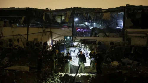 تظهر الصورة فرق الإنقاذ تعمل في موقع دمار كبير، حيث يتضح انهيار جزء من مبنى مع وجود أضواء في الخلفية، مما يعكس آثار الحرب الأمريكية الإسرائيلية على إيران.