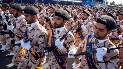 عناصر من الحرس الثوري الإيراني يرتدون زيًا عسكريًا خلال عرض عسكري، يحملون أسلحة، في سياق تصاعد التوترات مع الولايات المتحدة.