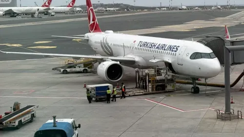 طائرة تابعة للخطوط الجوية التركية في مطار، مع عمال يقومون بتحميل الأمتعة، مما يعكس تأثير الاقتصاد التركي على قطاع النقل الجوي.