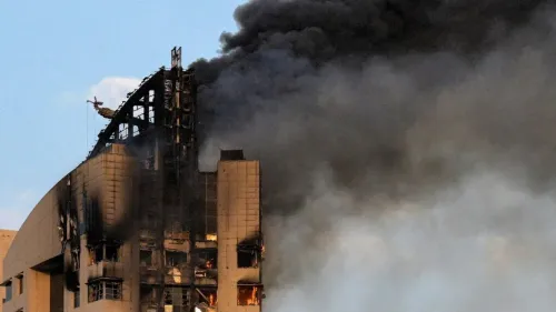 تصاعد الدخان من مبنى محترق، مما يعكس التوترات العسكرية في الشرق الأوسط وتأثيرها على الأمن الإقليمي والاستثمارات.