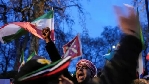 محتجون يحملون أعلامًا إيرانية ويهتفون في تظاهرة، مع أجواء مظلمة تعكس تصاعد الاحتجاجات ضد الحكومة الإيرانية.