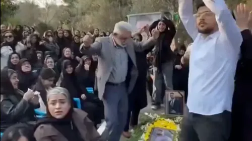 مشيعون يرقصون ويصفقون في مراسم تأبين، مع صور للقتلى وأجواء حزينة، تعبيرًا عن الحداد والاحتجاج في إيران.