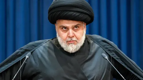 زعيم التيار الصدري مقتدى الصدر يرتدي الزي التقليدي ويخاطب الجمهور، مطالباً بوقف الهجمات من الأراضي العراقية لتحقيق السلام والاستقلالية الأمنية.