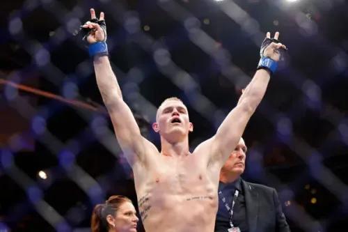 مقاتل UFC يرفع يديه انتصاراً داخل القفص في نزال بطولة فيلادلفيا، مع تركيز على سلسلة انتصارات Islam Makhachev التاريخية.