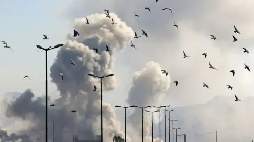 دخان كثيف يتصاعد من انفجار في منطقة حضرية، بينما تحلق الطيور في السماء، مما يعكس حالة الفوضى والاضطراب في السياق السياسي المعاصر.