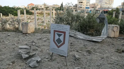تظهر الصورة آثار الدمار في مدينة صور اللبنانية، مع لافتة تحذيرية تشير إلى أهمية حماية المواقع الأثرية وسط الخراب.