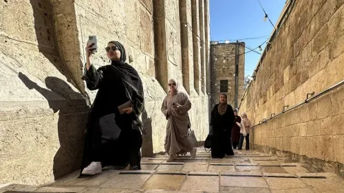 نساء فلسطينيات يرتدين الحجاب يسيرن في شارع ضيق بحي قديم، تعبيراً عن الحياة اليومية في الضفة الغربية المحتلة.