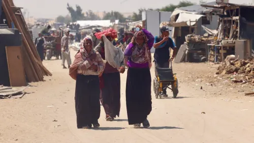 نساء يسيرون في شوارع مدينة رفح، وسط ظروف معيشية صعبة، مع وجود مخيمات وموارد محدودة في الخلفية.