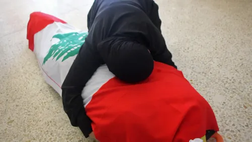 امرأة ترتدي الحجاب تضع رأسها على جثمان مغطى بعلم لبنان، تعبيراً عن الحزن في سياق الأحداث العسكرية الأخيرة.