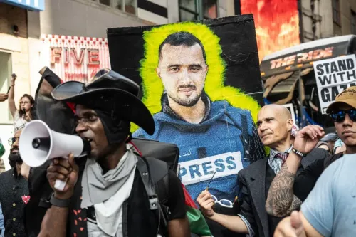 محتجون يحملون لافتة تظهر صورة صحفي يرتدي سترة "صحافة"، في مظاهرة تطالب بوقف الاعتداءات على الصحفيين في غزة.