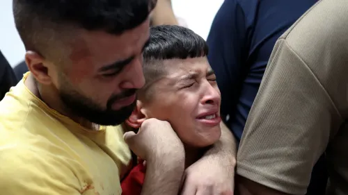 شاب فلسطيني يحتضن طفلاً يبكي بحرقة في مشهد يعكس مأساة قتل الأطفال الفلسطينيين في الضفة الغربية عام 2025.