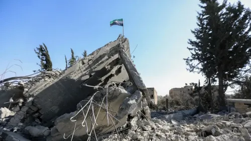 دمار هائل في بلدة كويا جنوب سوريا، مع العلم الوطني السوري يرفرف فوق الأنقاض، بعد قصف إسرائيلي أسفر عن مقتل خمسة أشخاص.