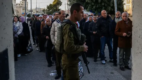 طابور طويل من المصلين الفلسطينيين عند حاجز إسرائيلي، بينما يقف جندي مسلح، في سياق قيود دخول المسجد الأقصى خلال رمضان.