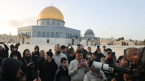 تجمع حشود من الفلسطينيين أمام المسجد الأقصى، حيث يلتقطون الصور ويظهرون تضامنهم في ظل التوترات المتزايدة.