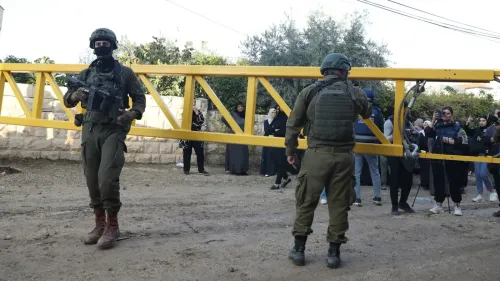 جنود إسرائيليون يحملون حاجزًا أصفر، بينما يتجمع محتجون في الخلف، في سياق التحذيرات من بناء جدار فاصل جديد في الضفة الغربية.