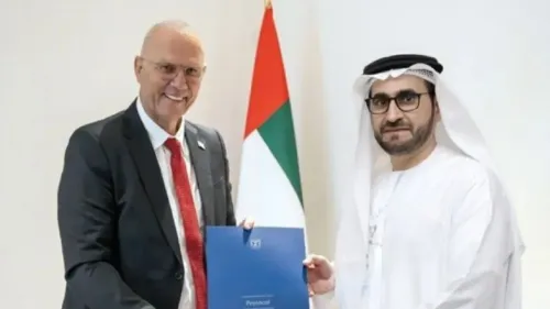 سفير إسرائيل لدى الإمارات، يوسف أفراهام شيلي، يتسلم وثيقة رسمية من مسؤول إماراتي، مع العلم الإماراتي خلفهم.