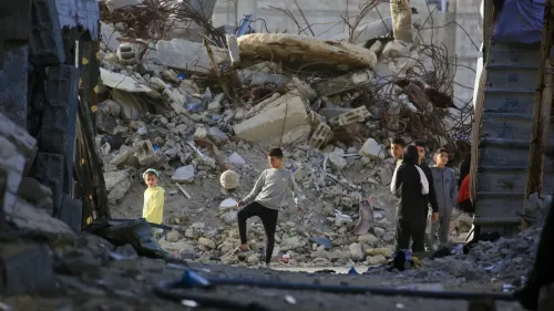 أطفال يلعبون في منطقة مدمرة في غزة، حيث تظهر الأنقاض خلفهم، مما يعكس آثار الصراع المستمر والدمار في المنطقة.