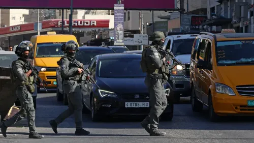 جنود إسرائيليون مسلحون يتقدمون وسط حركة مرور كثيفة في مخيم قلنديا بالقدس الشرقية خلال عملية عسكرية واسعة.
