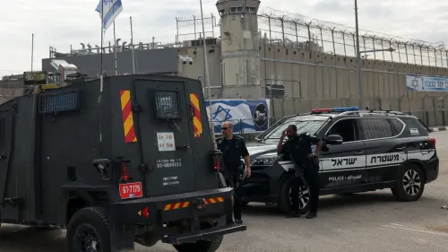 مركبة شرطة إسرائيلية أمام سجن محاط بسياج، مع وجود ضباط أمن. تعكس الصورة الأجواء الأمنية المتوترة حول مشروع قانون عقوبة الإعدام للأسرى الفلسطينيين.