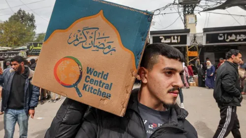 شاب يحمل صندوقًا يحمل شعار "المطبخ المركزي العالمي" في غزة، وسط حشد من الناس، مع التركيز على أهمية المساعدات الغذائية في ظل الأزمات الإنسانية.