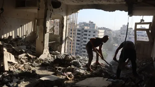 رجلان ينظفان أنقاض مبنى مدمر في غزة وسط دمار واسع نتيجة القصف الإسرائيلي المستمر على القطاع.