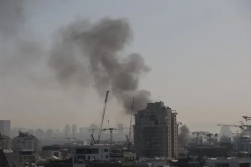 دخان كثيف يتصاعد من مباني في مدينة إسرائيلية، مما يعكس تأثير الحروب الحالية على الاقتصاد والأمن.