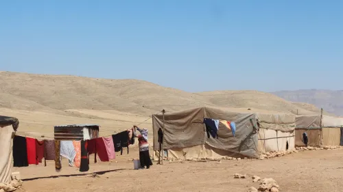 خيام فلسطينية في تجمع رعوي بالضفة الغربية مع ملابس معلقة على حبال في مشهد يعكس حياة الفلسطينيين في مناطق التهجير بسبب اعتداءات المستوطنين.