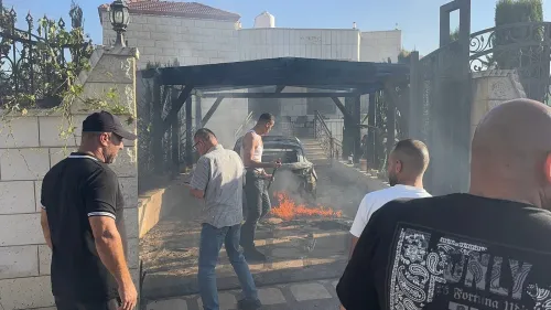 رجال فلسطينيون يحاولون إخماد حريق في سيارة أمام منزل متضرر جراء هجوم مستوطنين في قرية صرّة بنابلس بالضفة الغربية.