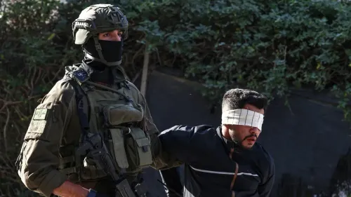 جندي إسرائيلي يرافق شاب فلسطيني معصوب العينين، في سياق مزاعم عن محاولة ابتزاز عائلة فلسطينية في الضفة الغربية.