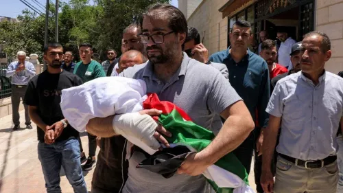 والد يحمل جثمان طفله سام فهد أبو هيكل، الذي قُتل برصاص جنود إسرائيليين، وسط حشود من المعزين في الخليل.
