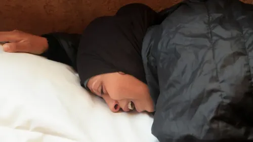 امرأة ترتدي الحجاب، ملقاة على وسادة، تعبر عن حزن عميق بعد الهجمات الإسرائيلية في غزة، مما يعكس معاناة المدنيين.