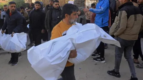 رجال يحملون جثثًا ملفوفة في أكياس بيضاء وسط حشد من الناس في غزة، بعد الغارات الإسرائيلية التي أسفرت عن مقتل العديد من الفلسطينيين.