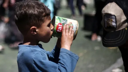 طفل فلسطيني يشرب من علبة طعام في غزة، يعكس المعاناة الإنسانية في ظل الظروف الصعبة التي يعيشها السكان.
